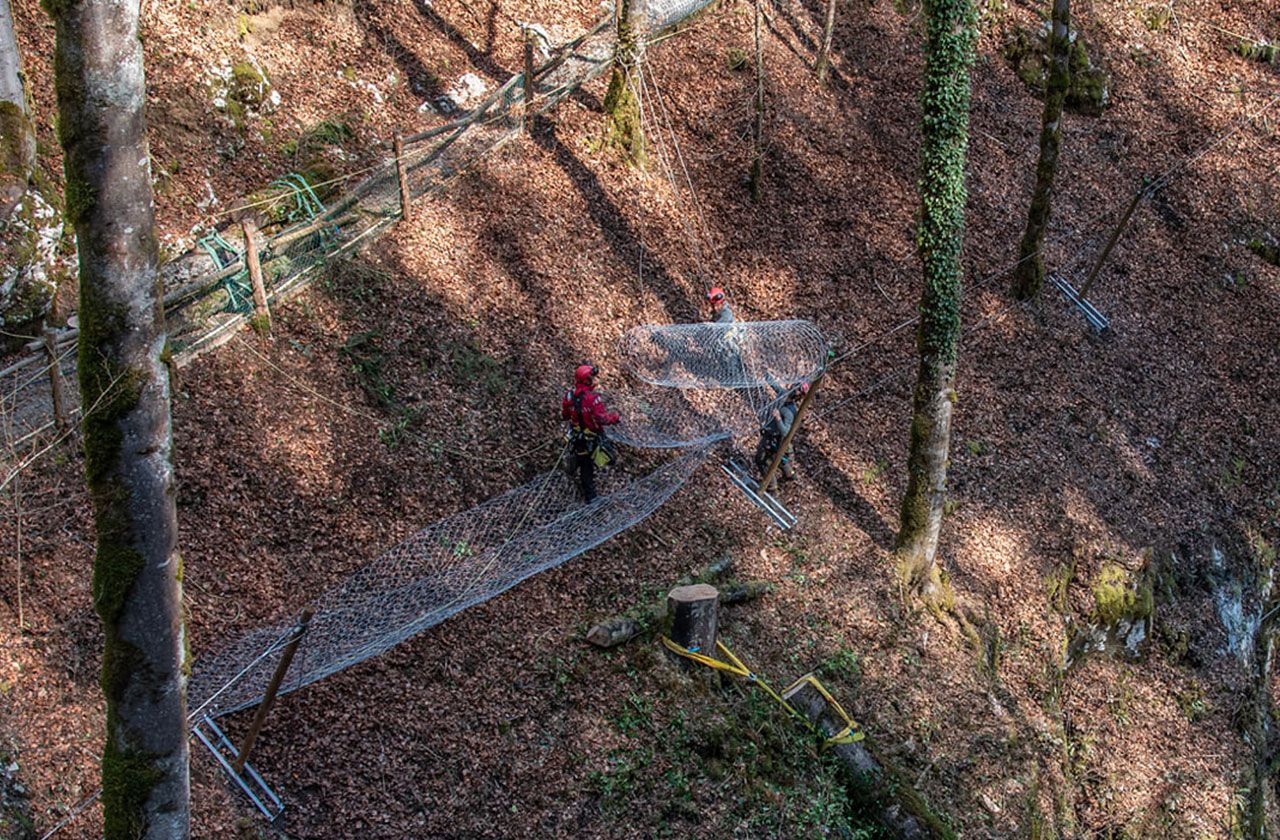 cordistes installant un filet de protection contre les chutes de pierres en milieu forestier