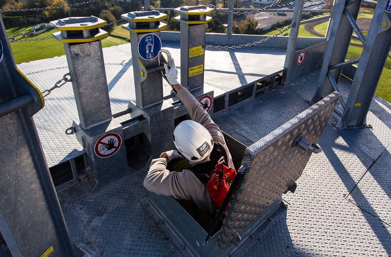 Opérateur en formation se sécurisant pour sortir sur une plateforme en hauteur